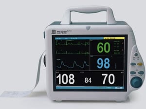 Monitor multiparametrico PM-8000 con display che mostra tracciati ECG, frequenza cardiaca, saturazione ossigeno (SpO₂) e valori di pressione arteriosa.